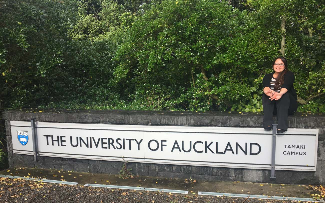 Anitra on a sign saying "the University of Auckland" in New Zealand.