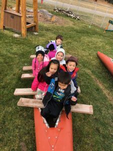 Children set out on a fishing trip after cooperatively constructing seats on their canoe.