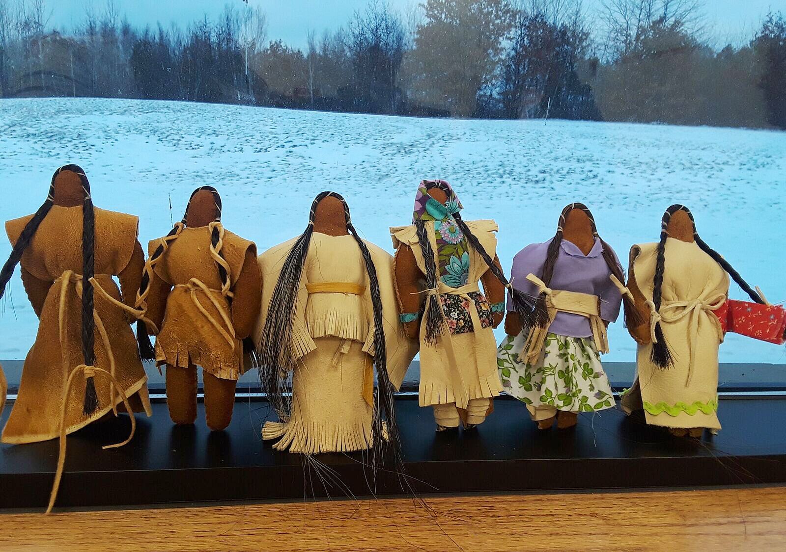 A lineup of all of the completed faceless dolls done at the workshop in a window seal.