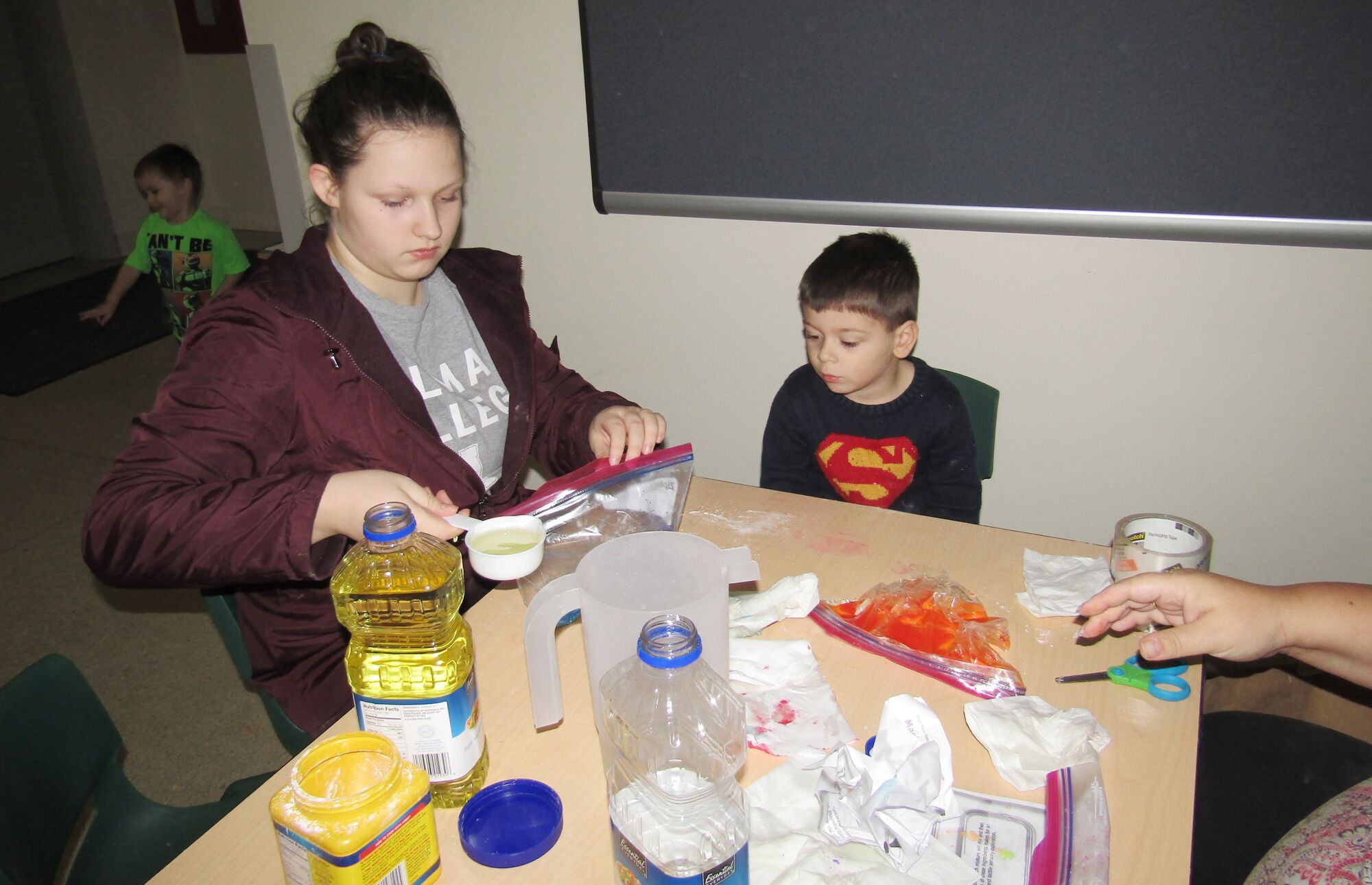 siblings working together to fill bags with oil, corn starch and liquid water color